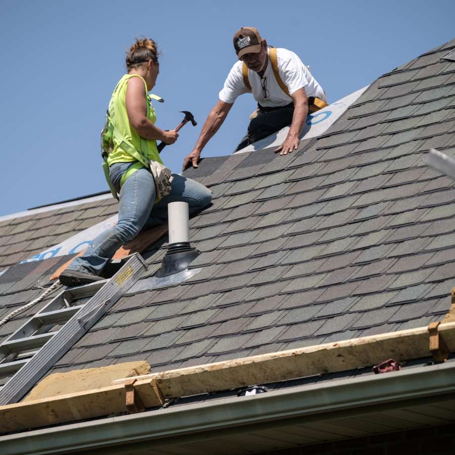 workers nailing shingles on a slanted roof